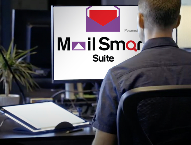 man looking at desktop computer that displays Mail Smart Suite